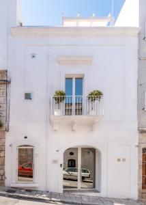 un edificio blanco con balcón y coche en La Bella Ostuni Suites, en Ostuni