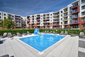 une piscine avec un toboggan et des chaises ainsi qu'un appartement dans l'établissement Klif Apartamenty Polanki Park, à Kołobrzeg