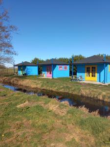 a row of colourful houses next to a river at Camping de Oude Rijn in Ter Aar