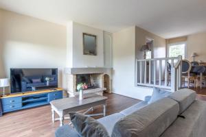 ein Wohnzimmer mit einem Sofa und einem TV in der Unterkunft Nice flat in a beautiful estate 15 min by walk from Deauville - Welkeys in Tourgéville