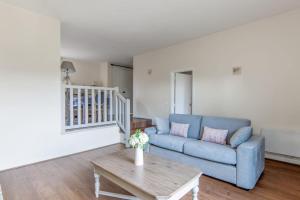 ein Wohnzimmer mit einem blauen Sofa und einem Tisch in der Unterkunft Nice flat in a beautiful estate 15 min by walk from Deauville - Welkeys in Tourgéville