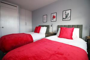 two beds with red pillows in a bedroom at CHANDOS - Spacious Home, High Speed Wi-Fi, Free Parking, Garden in Swindon