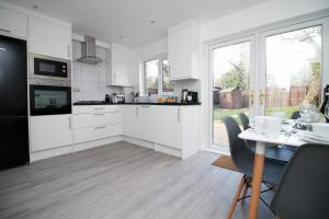 una cocina con armarios blancos y una mesa con sillas. en CHANDOS - Spacious Home, High Speed Wi-Fi, Free Parking, Garden, en Swindon