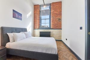 Un dormitorio con una cama y una pared de ladrillo. en No 2 at Simpson Street Apartments Sunderland, en Sunderland