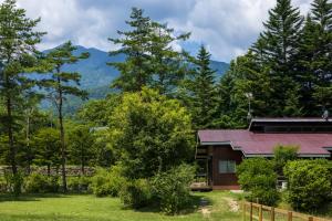 a house in the woods with mountains in the background at アルプスシャレー in Hokuto