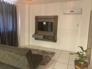 ein Wohnzimmer mit einem Sofa und einem TV an der Wand in der Unterkunft Kitnet Beira Rio in Alfredo Wagner
