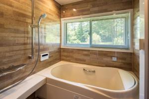a bath tub in a bathroom with a window at アルプスシャレー in Hokuto +22 photos