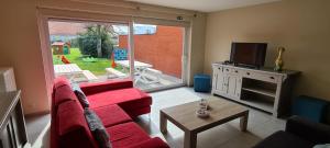 - un salon avec un canapé rouge et une télévision dans l'établissement Holiday Home Weekendhuisje, à Nieuport