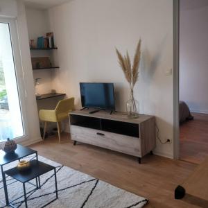 a living room with a flat screen tv on a cabinet at Direct Aéroport et centre historique de Bordeaux in Mérignac
