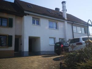 ein weißes Haus mit zwei Autos davor geparkt in der Unterkunft Ferienwohnung Dinkelbergblick Öflingen in Wehr