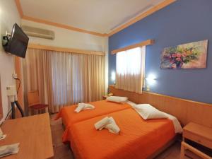 a hotel room with two beds and a tv at Possidon in Agia Marina Aegina