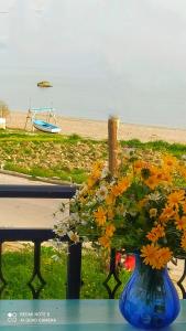 eine blaue Vase mit Blumen auf einem Tisch am Strand in der Unterkunft Socrates sea view in Kámpos