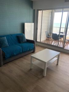 - un salon avec un canapé bleu et une table basse dans l'établissement Studio face mer, à Saint-Michel-Chef-Chef
