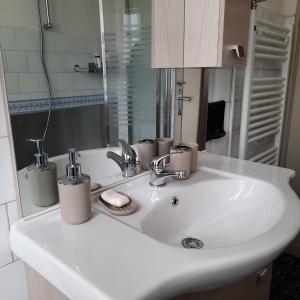 La salle de bains est pourvue d'un lavabo blanc et d'un miroir. dans l'établissement Appartamento Legnone - Your Mountain Holiday, à Tremenico
