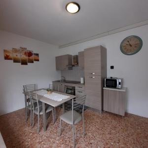 une cuisine avec une table, des chaises et une horloge dans l'établissement Appartamento Legnone - Your Mountain Holiday, à Tremenico