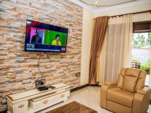 a living room with a tv on a stone wall at Jengel 2 bedroom Apartment in Entebbe