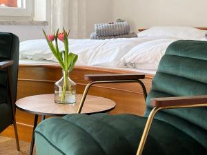 - un salon avec un lit et un vase avec des fleurs sur une table dans l'établissement Pension Kitty, à Pörtschach am Wörthersee