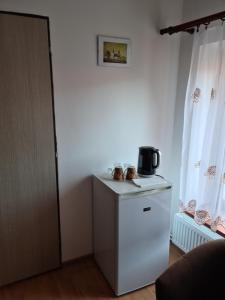 a small white refrigerator in a room with curtains at Penzión Larix Blatnica in Blatnica