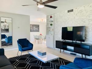 a living room with a flat screen tv and blue chairs at Blue-Door RESIDENCE @Maywood in San Antonio