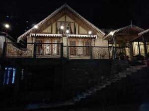 a house with a balcony and stairs at night at Marigold Manor Homestay in Darjeeling