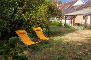 dwa żółte krzesła siedzące w trawie na podwórku w obiekcie Logisfontainebleau w mieście Villiers-sous-Grez
