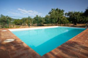 uma piscina azul com cerca e árvores em Casa Rural La Serrana de Aracena em Aracena
