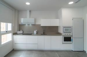 una cocina blanca con armarios y electrodomésticos blancos en AAC Málaga - Apartamento con terraza, muy amplio, totalmente equipado, cerca del centro y nuevo! en Málaga