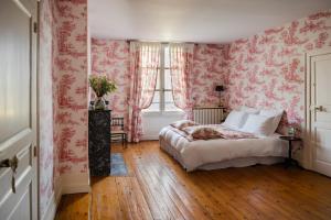 a bedroom with pink floral wallpaper and a bed at MAISON HULOTTE in Amboise