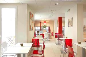 uma sala de jantar com cadeiras vermelhas e mesas num restaurante em ibis Roscoff em Roscoff