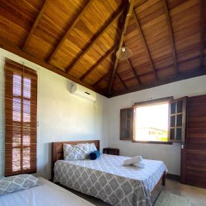a bedroom with two beds and a wooden ceiling at Bahia Soul - Bangalô Sol - Grupo Barril Hospedagens in Marau