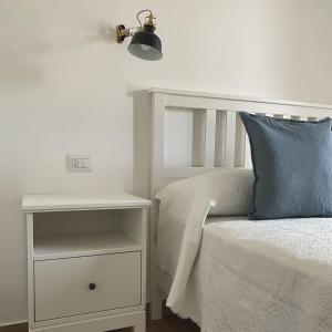 a white bed with a blue pillow next to a nightstand at Casa Maria luxury B&B in Ischia