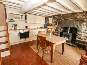 cocina con mesa de madera y chimenea en 2 Bwth Mawr, en Barmouth
