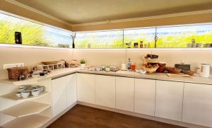 a kitchen with white cabinets and a large window at Pension Windrose in Prerow