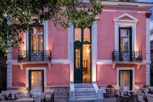 a pink building with tables and chairs in front of it at Nafsimedon Hotel in Nafplio