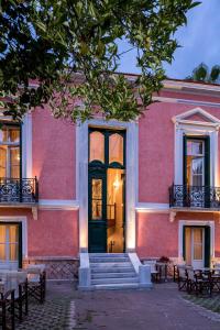 a pink building with a black door and stairs at Nafsimedon Hotel in Nafplio