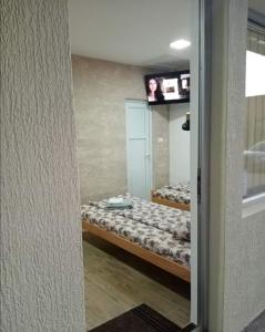 a room with two beds and a tv on a wall at Apartman Oreol in Priboj