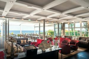 a lobby with red chairs and tables and the ocean at Strandhotel Ostseeblick in Heringsdorf