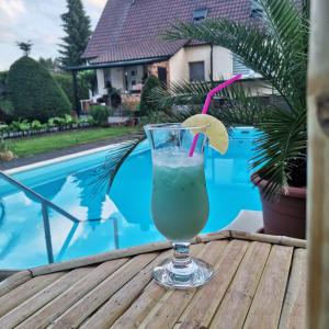 een drankje zittend op een tafel naast een zwembad bij Spreewaldpension Zickert in Lübben