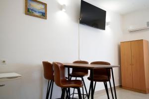 a dining room table with chairs and a television on a wall at Apartments Roberta in Kožino