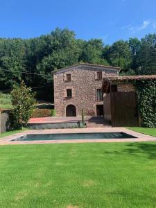 una casa de piedra con un patio con césped en CAN VOLAN, en Sant Pere Despuig