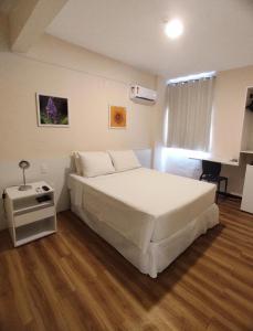a bedroom with a large white bed and a desk at Hotel Acalanto in Feira de Santana