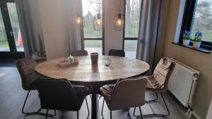 a wooden table with chairs around it in a room at Vakantiewoning Maas en Waal 100 in Ewijk