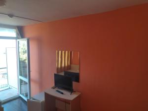 a room with an orange wall with a computer and a mirror at Hotel Zora in Kranevo