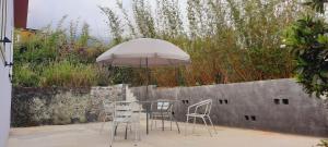 a table with chairs and an umbrella next to a wall at LaKlé ... in Cilaos
