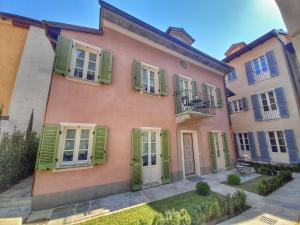 a pink house with green shutters on it at Alessia Home in Cannobio