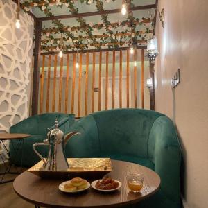 a coffee table with a teapot on a green couch at اضواء السلام للشقق المخدومة in Medina