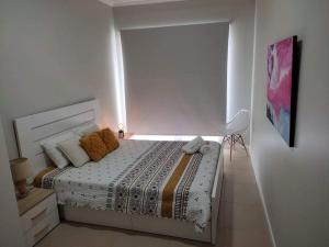 a white bedroom with a bed and a chair at Cantinho do Sonho in Maia