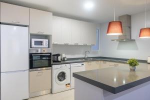 a kitchen with white cabinets and a washer and dryer at Brand New Apartment With Super Comfortable Beds in Valencia