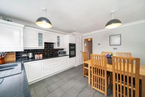 a kitchen with white cabinets and a wooden table at Dalmarnock Stay in Glasgow