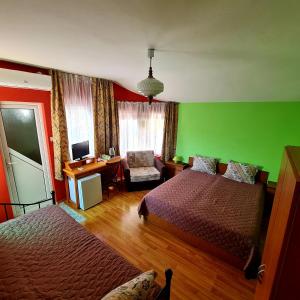 1 dormitorio con 2 camas y pared verde en Fema Guest House en Balchik